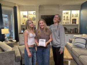 Sarah VanHoose with her daughters Harper and Jordan holding the Teens & Money guide